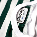 Close-up of the ribbed collar and Beans Basic Men brand tag on a green striped t-shirt.